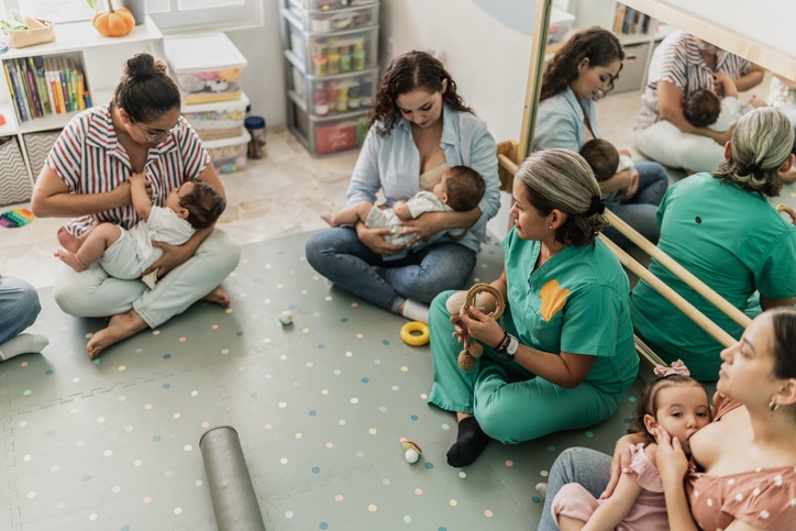 Mature woman teaching mothers how to breastfeed their babies at support group